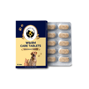 A product presentation featuring a navy blue and beige "Worm Care Tablets" box with images of a cat and dog, placed next to an open blister pack of 10 speckled tan tablets on a textured grey surface.